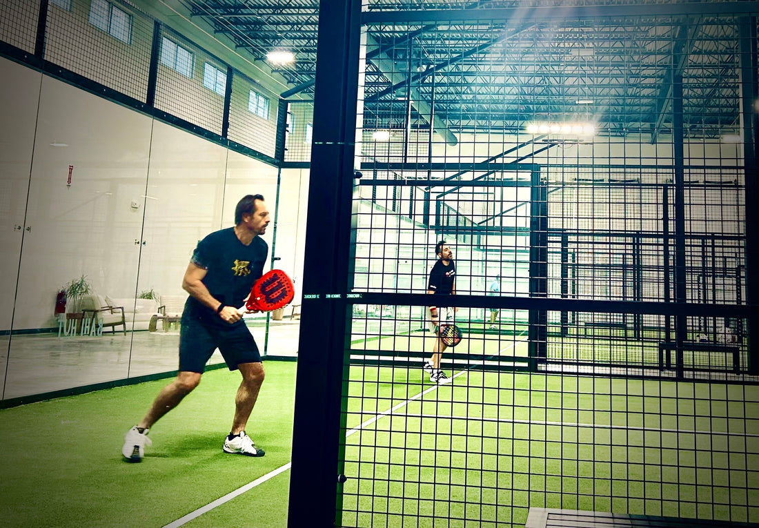 Men playing a game of Padel on an indoor court.